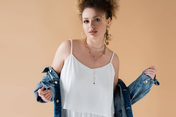Portrait of woman in white top and denim jacket posing isolated on beige  - Photo, Image