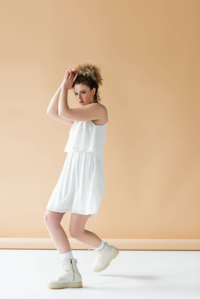 Stílusos modell fehér ruhák pózol bézs háttér  - Fotó, kép