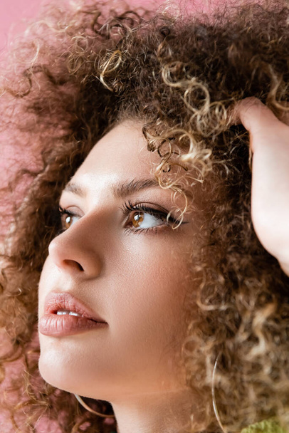 Portrait of young curly woman touching hair isolated on pink  - Foto, Imagem