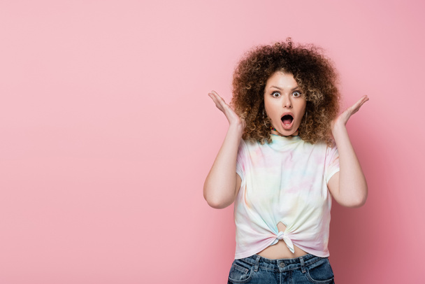 Astonished woman in t-shirt looking at camera on pink background - Фото, зображення