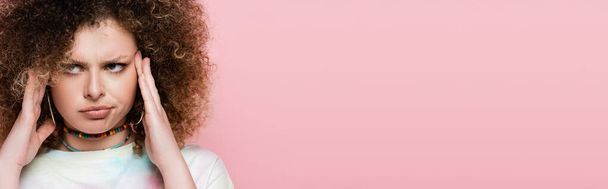 Pensive curly woman touching head isolated on pink, banner  - Foto, Imagen