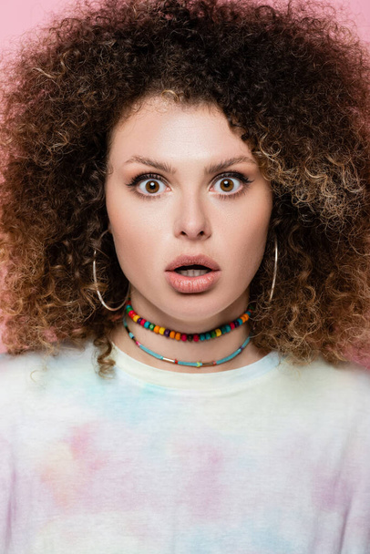 Shocked curly woman looking at camera isolated on pink  - Foto, Imagen