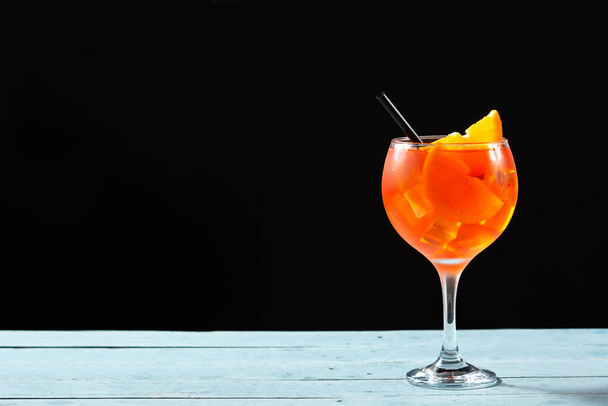Glass of aperol spritz cocktail on blue wooden table and black background. Copy space - Foto, immagini