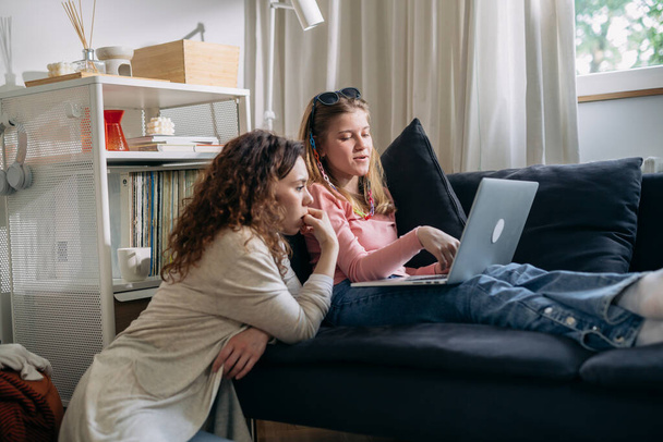 caucasian mother and her daughter sitting on sofa at home and using laptop computer - Valokuva, kuva