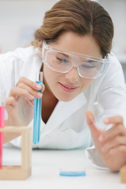chemist looks at blue liquid in the test tube - Фото, зображення
