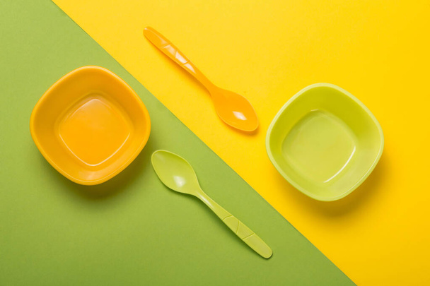 dos cucharas y dos platos de amarillo y verde sobre un fondo de papel amarillo y verde con una línea diagonal de demarcación, el concepto de platos y alimentos - Foto, Imagen