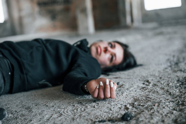 Corpse of female victim of crime lying down on the ground of abandoned building. - Φωτογραφία, εικόνα