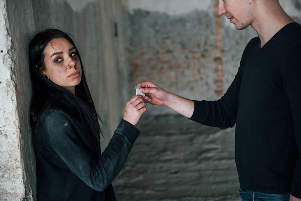 Two people standing with illegal drugs in little package indoors. - Fotó, kép