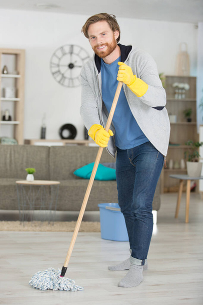 young man mopping floor - Фото, изображение
