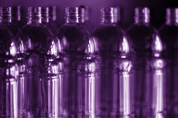many plastic bottles in lilac backlight are ranked in a row, the concept of plastic packaging and ecology - Foto, Imagen