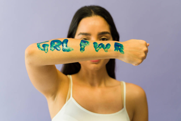 Feminist young woman showing a message of girl power on her arm during a women's movement march - Foto, afbeelding