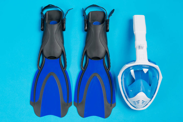 paar blauwe flippers en full face masker voor duiken op een blauwe achtergrond, het concept van reizen en vrije tijd, platte lay - Foto, afbeelding
