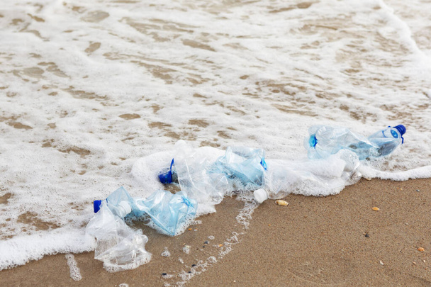 minimal concept of environmental pollution, plastic bottles lie on the sea beach, near the water, close-up - Foto, Bild