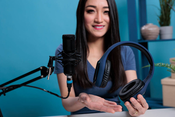 Asian vlogger creator holding headset talking into studio microphone - Foto, Bild