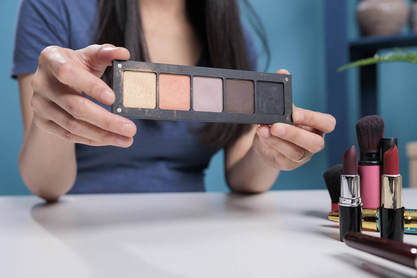 Social media influencer holding makeup palette doing cosmetic review - Foto, afbeelding