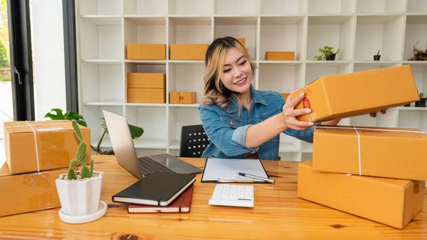 Starting a small business, SME entrepreneur or freelance, young Asian woman using a laptop computer with a box. successful women at work Shipping, Packaging, Online Marketing, SME Business Ideas - Fotoğraf, Görsel