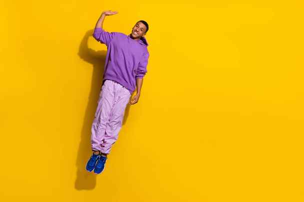 Full length body size view of attractive trendy cheerful guy jumping having fun waving hi isolated on bright yellow color background - Fotó, kép