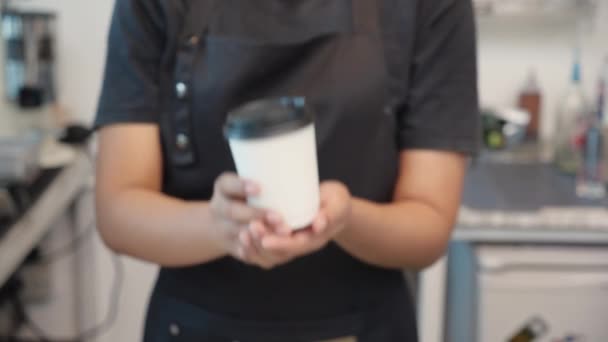 Hands of barista giving takeaway coffee cup to customer in the cafe, closeup hands of staff serving beverage to client in the coffee shop, waitress and ordering, one person, lifestyles concept. - Video