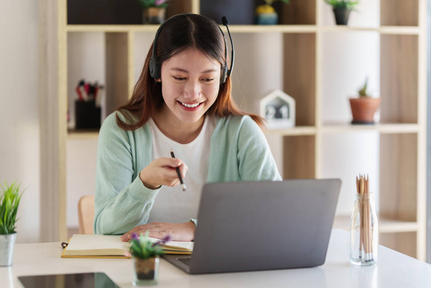 Sonriente asiática atenta estudiante que estudia en línea clase. Concepto de educación e-learning. - Foto, imagen