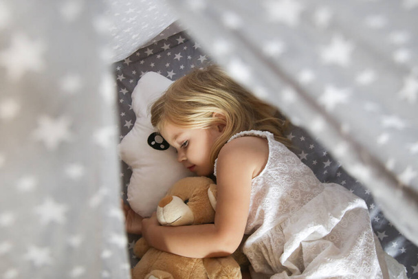 Yıldız desenli ve bulut şekilli yastık şeklinde yatak çarşaflarında uyuyan tatlı kız. - Fotoğraf, Görsel