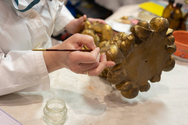 Lady expérimentée Restauration d'une petite statuette dorée avec une brosse très fine dans son atelier d'art. - Photo, image