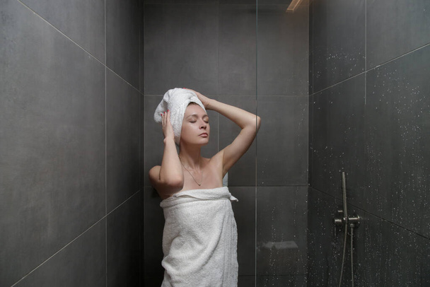 Young caucasian woman wrapped in towels in shower cabin - Foto, Imagem