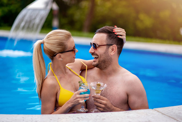 Couple drinking coctails in the swimming pool. - Fotoğraf, Görsel
