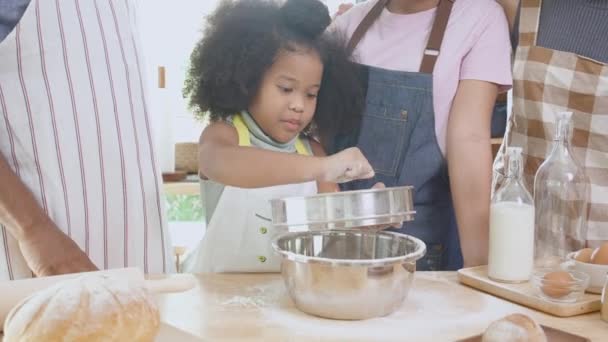 Familia afroamericana usando delantal para cocinar panadería o pan con harina juntos en la cocina en casa, padres e hijos pequeños preparando la comida con diversión y juguetón, relación y pasatiempo. - Metraje, vídeo