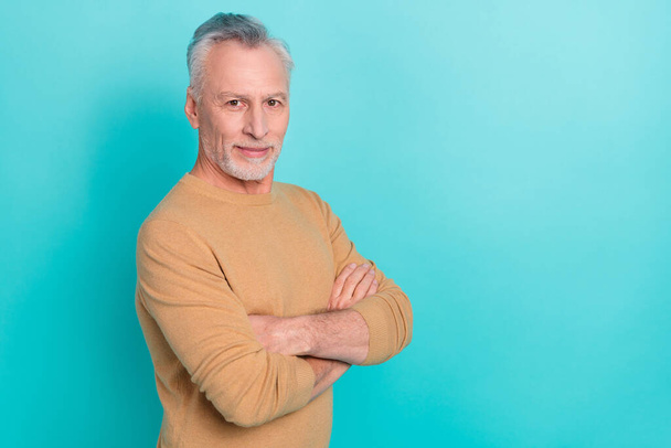 Photo of half turned positive aged man crossed hands look camera isolated on turquoise color background - Fotografie, Obrázek