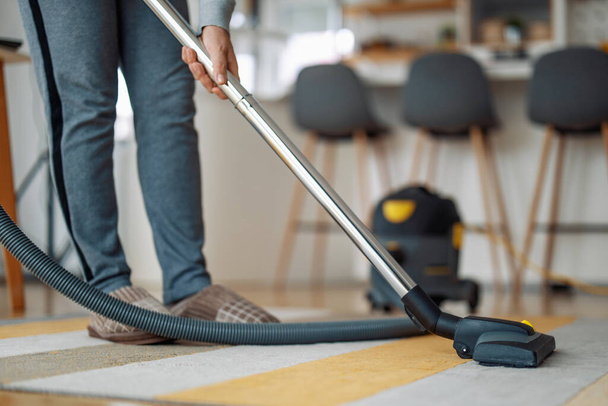 Femme utilisant un aspirateur pendant le nettoyage de tapis dans la maison. - Photo, image