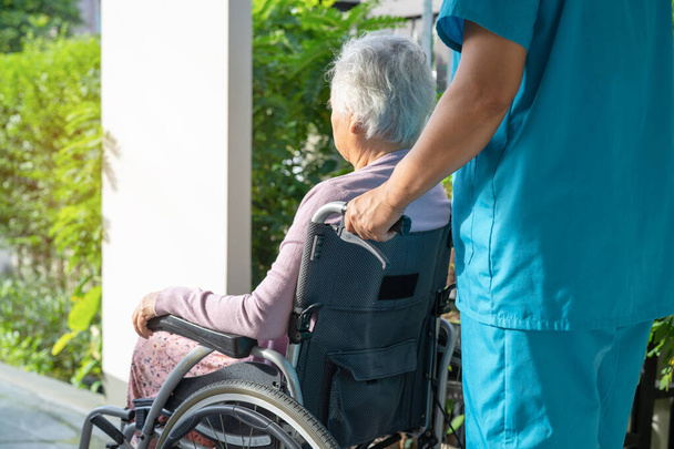 Cuidador ayuda y cuidado Asiática anciana o anciana anciana paciente sentada en silla de ruedas en rampa en el hospital de enfermería, concepto médico fuerte saludable - Foto, Imagen