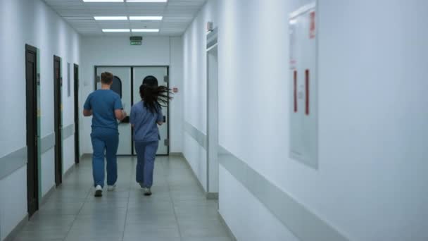 Unknown doctor nurse moving down hallway back view. Surgeon consulting woman. - Πλάνα, βίντεο