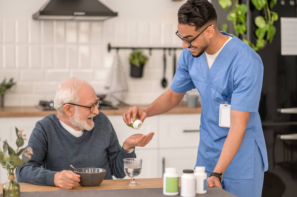 Enfermera en casa dando pastillas a un anciano - Foto, imagen