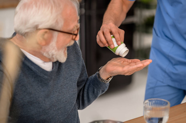 Elderly person receiving a medication from the pill bottle - Фото, зображення