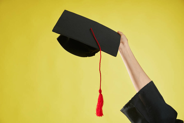 Female hand raising, holding, showing mortarboard. - Foto, afbeelding