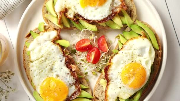 Dilimlenmiş avokado sandviçi ve kızarmış yumurta ile lezzetli sağlıklı bir kahvaltı. - Video, Çekim