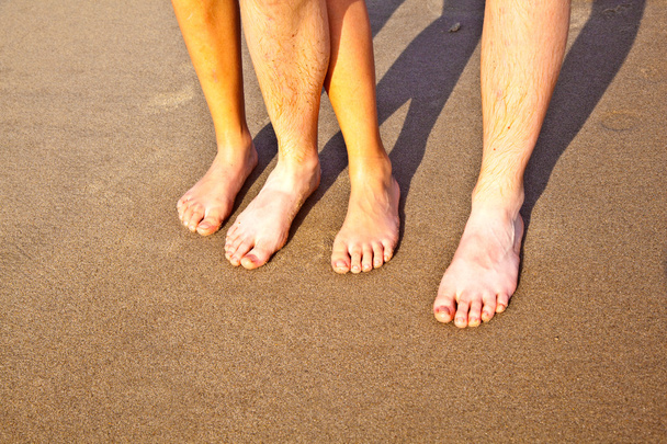 voeten van vader en zoon op het natte zand van het strand - Foto, afbeelding
