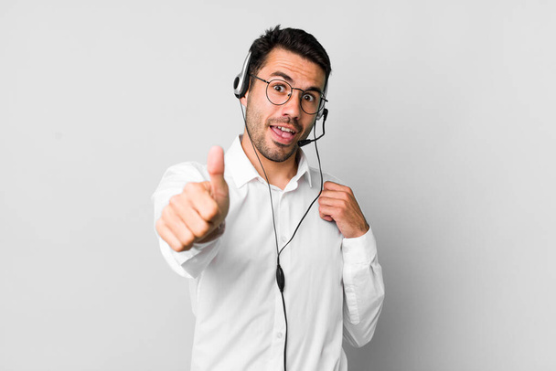 young adult hispanic man feeling proud,smiling positively with thumbs up. telemarketer concept - Valokuva, kuva