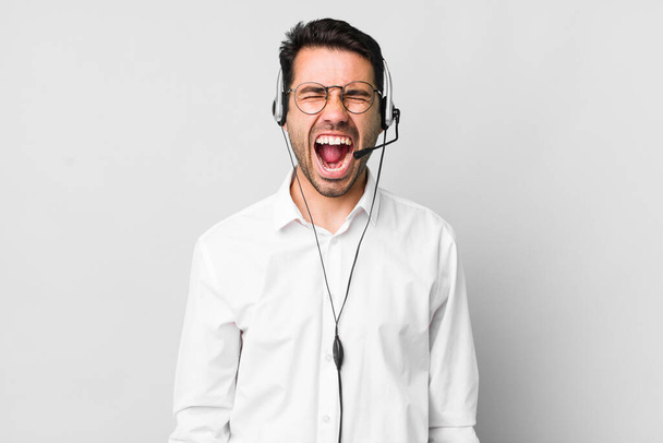 young adult hispanic man shouting aggressively, looking very angry. telemarketer concept - Foto, Imagen