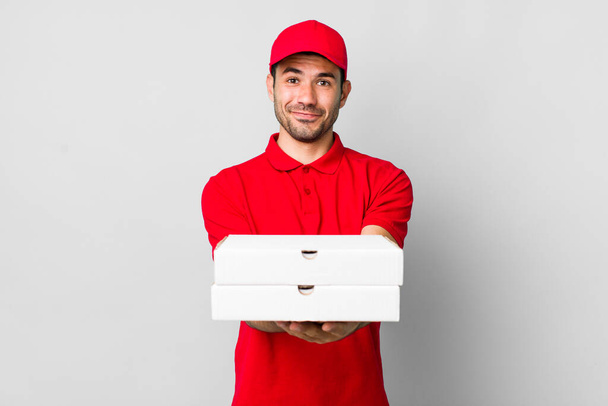 young adult hispanic man smiling happily with friendly and  offering and showing a concept. pizza delivery concept - Fotografie, Obrázek