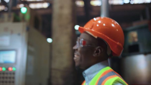 Ingeniero alegre hombre sonriendo en enorme fábrica moderna con uniforme de seguridad. - Foto, imagen
