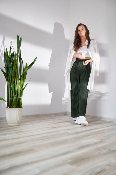 photo of a girl in green pants near a green plant - 写真・画像