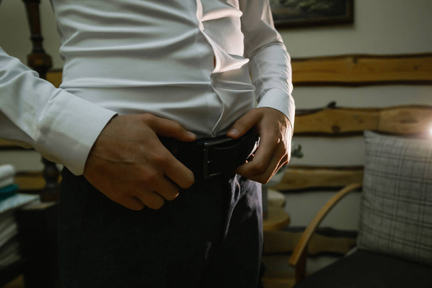 A man adjusts his belt and zips his pants, close-up. - Photo, Image