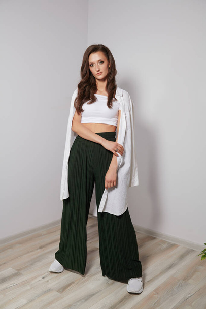 girl in green pants and a white shirt in a bright room - Фото, зображення