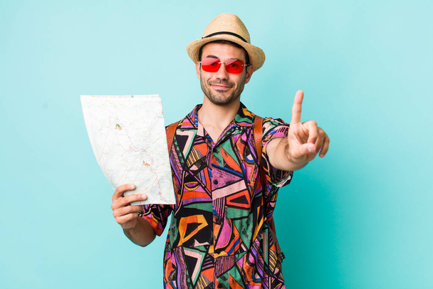 young adult hispanic man smiling and looking friendly, showing number one. tourist concept - Photo, Image
