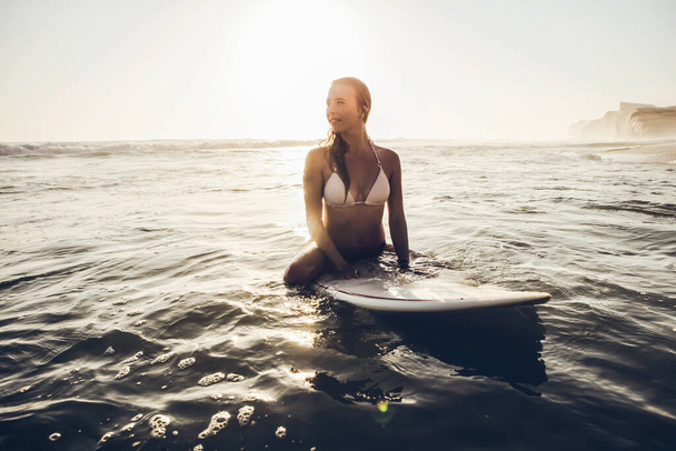 Beautiful young woman sitting on the surfboard waiting for set of wave - Foto, Imagem