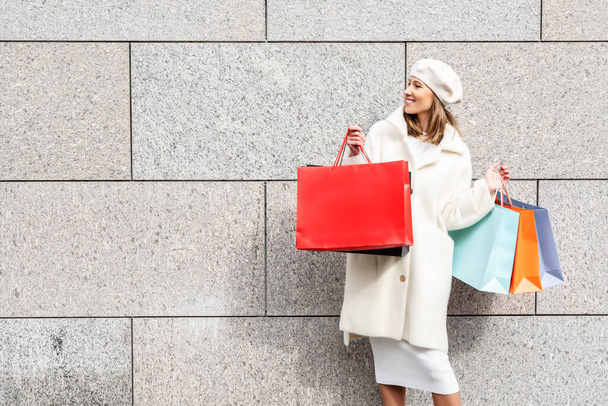 Woman with shopping bags near the empty wall for your copy space. Shopping or sales template. - Photo, Image