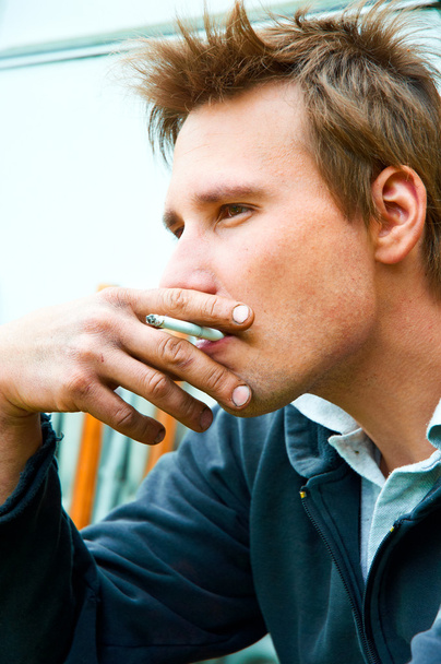 Gros plan d'un jeune homme avec cigarette dans la bouche
 - Photo, image