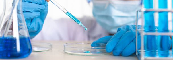 Scientists are carrying blue chemical test tubes to prepare for the determination of chemical composition and biological mass in a scientific laboratory, Scientists and research in the lab Concept. - Photo, image