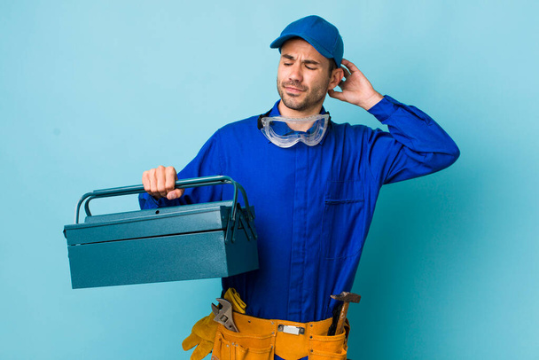 young adult hispanic man smiling happily and daydreaming or doubting. toolbox concept and plumber - Foto, Imagem